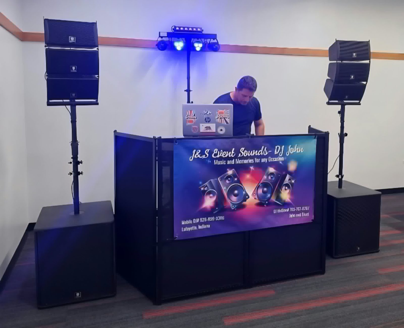 DJ John at the J&S Event Sounds DJ booth with speakers and stage lights